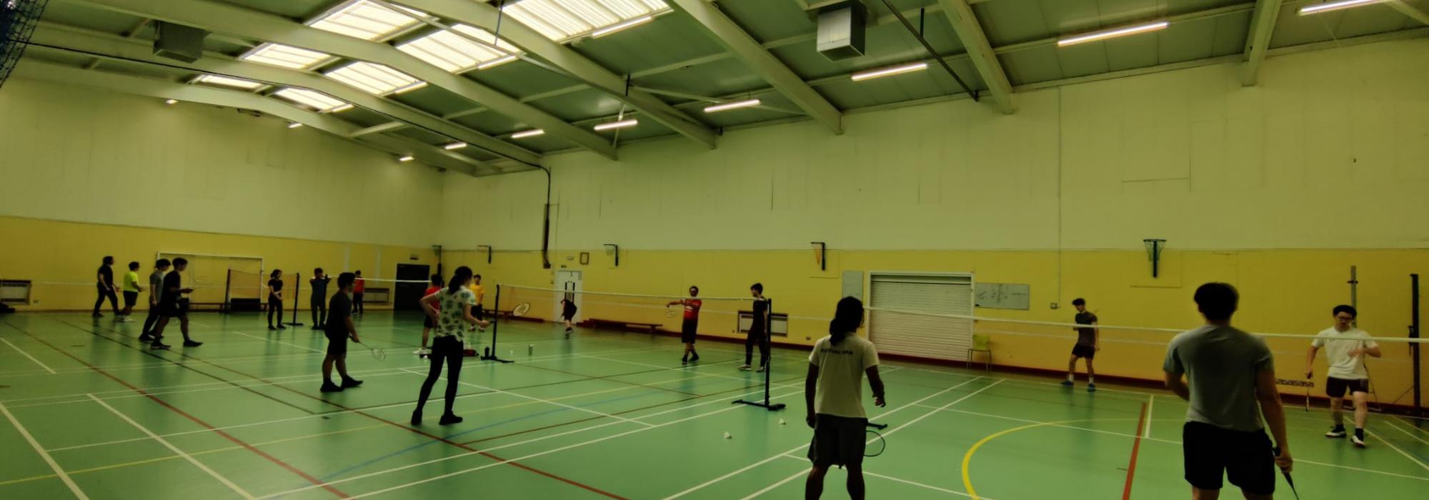 Badminton players practising on the courts Badminton players practising on the courts
