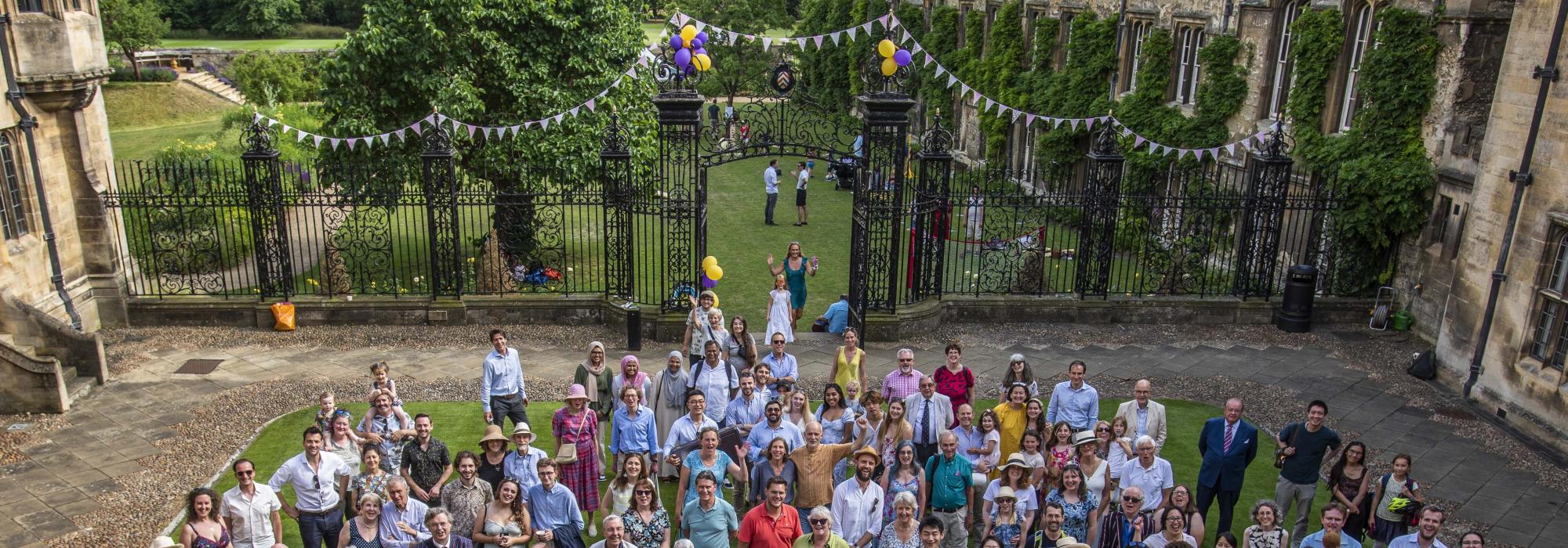 A large group of people standing on the lawn looking up at the camera